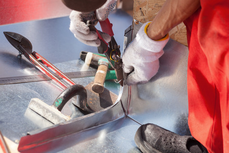 Roofer builder worker finishing folding a metal sheet using metal shearsの写真素材