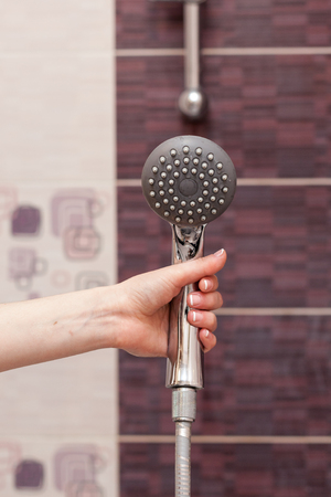 Housewife holds in her hand cleen and Ñlosed off rain shower head in the bathroom.の写真素材