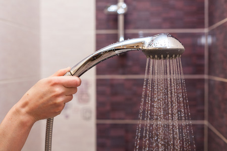 Water streams flow out of working shower head right down.の写真素材
