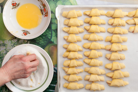 Process of cooking small croissants with cherry for breakfast. Preparation of baking on a rustic white background. Egg-based breading. Breaded with sugarの写真素材