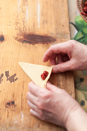 Process of cooking small croissants with cherry for breakfast. Preparation of baking on a rustic wooden backgroundの写真素材