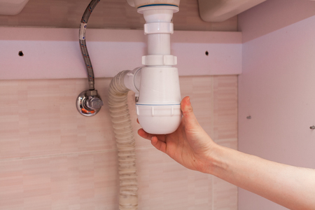 Clearing of blocked hammered polluted plastic U siphon for wash basin, sanitary devices, plumbing fixtures special means cleanser. Plumbing siphon. White plumbing siphon assembly.の写真素材