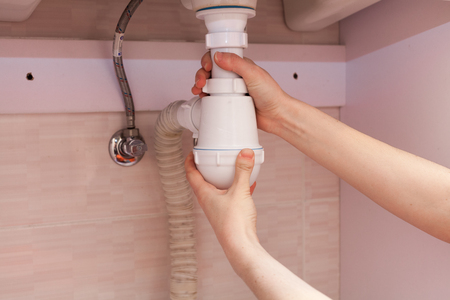 Clearing of blocked hammered polluted plastic U siphon for wash basin, sanitary devices, plumbing fixtures special means cleanser. Plumbing siphon. White plumbing siphon assembly.の写真素材