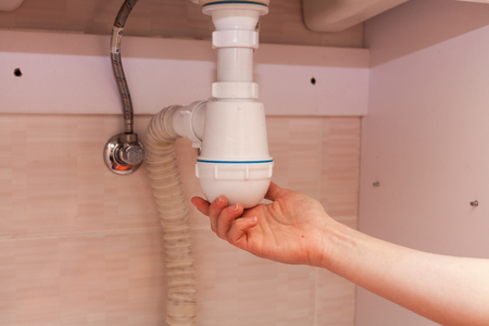 Clearing of blocked hammered polluted plastic U siphon for wash basin, sanitary devices, plumbing fixtures special means cleanser. Plumbing siphon. White plumbing siphon assemblyの写真素材