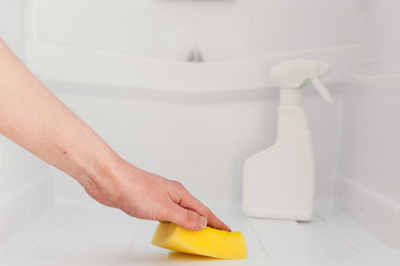 Woman's hand cleaning white fridge with yellow sponge at kitchen.の写真素材