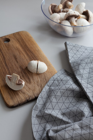 Fresh sliced mushrooms at wooden cutting board. Chopping food ingredients. Food background of fresh champignons at the old cutting board with copy spaceの写真素材