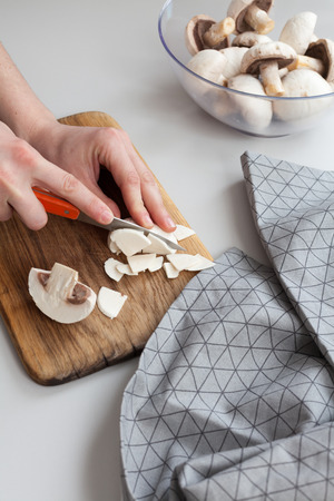 Fresh sliced mushrooms at wooden cutting board. Woman chopping food ingredientsの写真素材