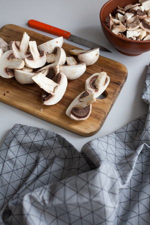 Fresh sliced mushrooms at wooden cutting board. Chopping food ingredients. Food background of fresh champignons at the old cutting board with copy spaceの写真素材