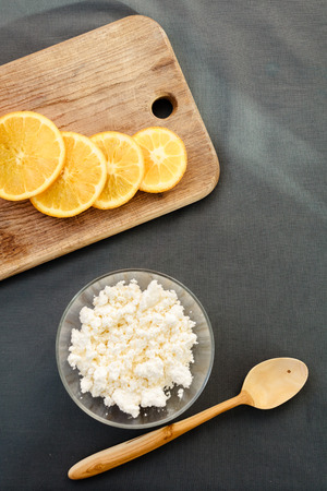 Cottage cheese with orange on cutting board with wooden spoon.の写真素材