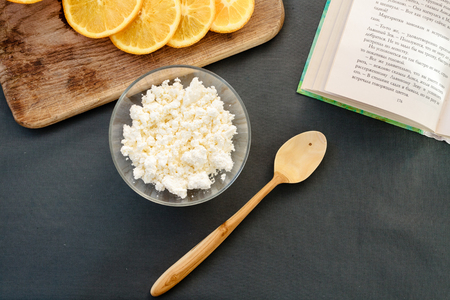 Cottage cheese with orange on cutting board with wooden spoon.の写真素材