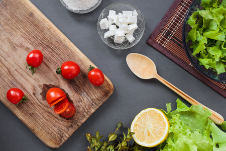 Salad of vegetables with spices. On a wooden surface. Pieces of vegetables, cherry tomatoes, spices, basil.の写真素材