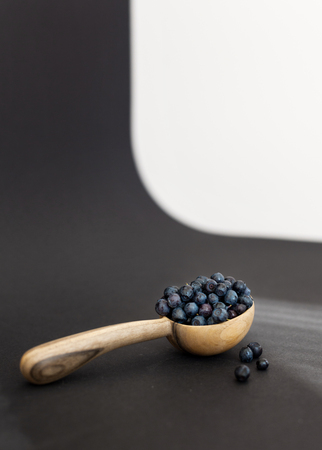 Fresh juicy blueberry fruits on a wooden spoon against a dark background.の写真素材