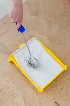 Close-up of mans hands using paint roller while working indoorsの写真素材