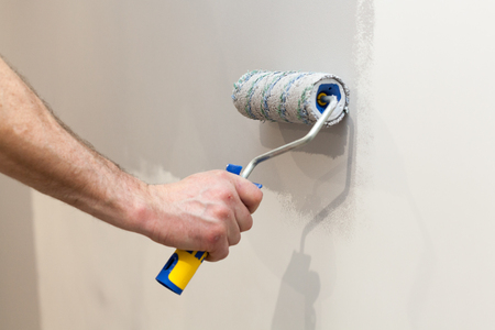 Worker painting wall in room. Painting walls with a rollerの写真素材