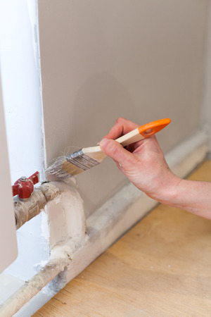 Worker painting wall in room. Painting walls in a corner with a paint brush.の写真素材