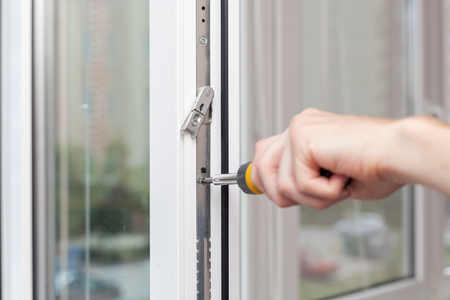 Handyman repairs plastic window with screwdriver.の写真素材