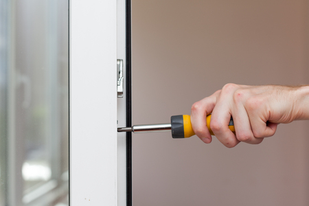 Handyman repairs plastic window with screwdriver close-upの写真素材