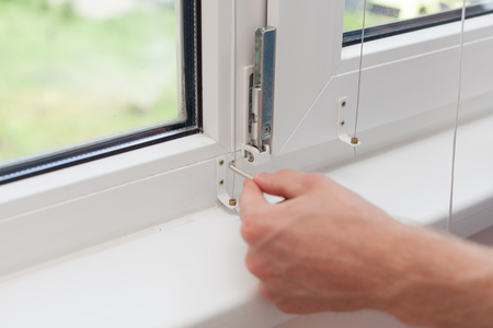 Handyman repairs plastic window with a hexagon. Workman adjusts the operation of the plastic window.の写真素材