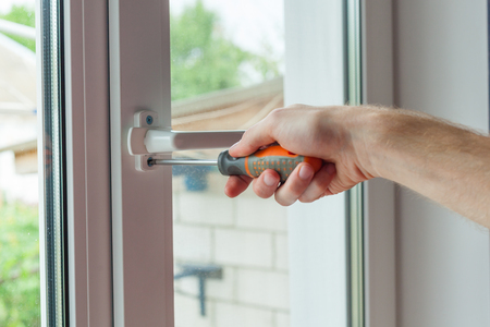 Close-up, hand with a screwdriver tightens the fixing screw of the window limiteの写真素材