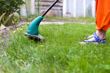 Garden equipment. Woman mowing the grass with a trimmerの写真素材