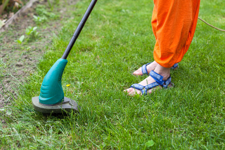 Garden equipment. Woman mowing the grass with a trimmerの写真素材