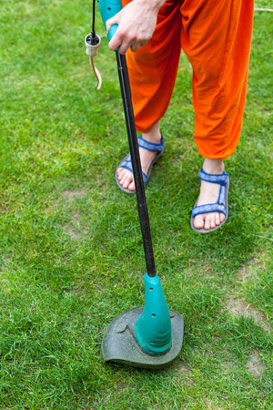 Garden equipment. Woman mowing the grass with a trimmerの写真素材