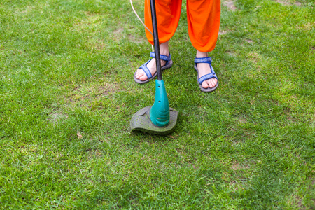 Garden equipment. Young woman mowing the grass with a trimmerの写真素材