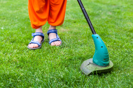 Garden equipment. Young woman mowing the grass with a trimmerの写真素材