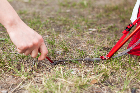  Closeup of girl hands placement of red camping tent, macro shot of peg and grassの写真素材