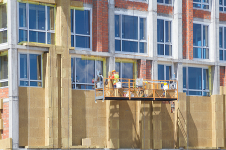 Construction workers insulating house facade with mineral rock wool installation. External wall insulation system (or EWIS) mineral wool for energy savingの写真素材