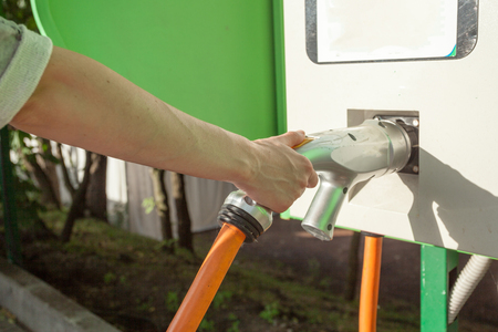 Electric car charging vehicle energy power for environmental friendly. Woman holding charging cable of electric car.の写真素材