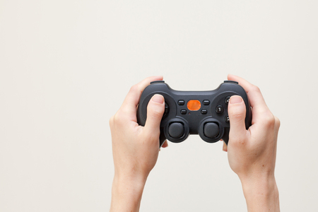 A woman is holding a joystick. Gamepad in hands on a white background.の写真素材
