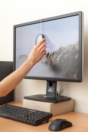 Workspace with calibrator or profiler attached to laptop's display to get accurate colors. Woman hand installs the calibrator on the monitor to adjust the color.の写真素材