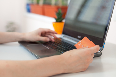 Hand of a woman making purchases through the Internet. Online Shopping. Focus on the hand and on the card. Paying with credit card onlineの写真素材