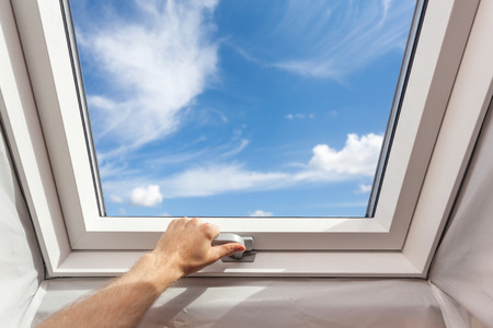 Man close new skylight (mansard window) in an attic room against blue skyの写真素材