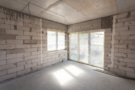 New house under construction. Aerated concrete blocks, cement brickwork walls, plastic window, electric wiring installation. Cement covering in empty roomの写真素材