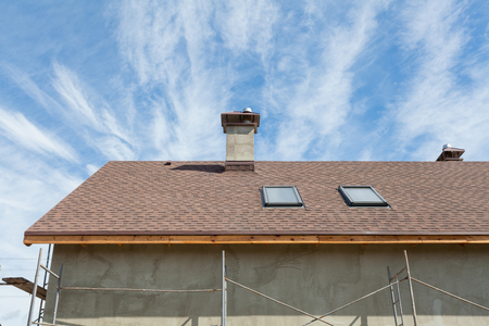 New roof with skylight, asphalt roofing (shingles) and chimney. Roof with mansard windows.の写真素材