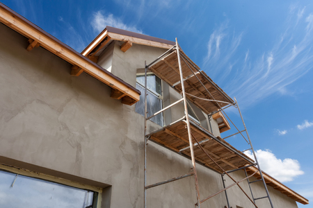 Exterior view of new house under construction and painting. Scaffolding for exterior plastering at homeの写真素材