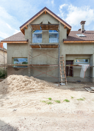 Exterior view of new house under construction and painting. Scaffolding for exterior plastering at homeの写真素材
