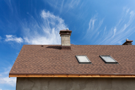 New roof with skylight, asphalt roofing (shingles) and chimney. Roof with mansard windows .の写真素材