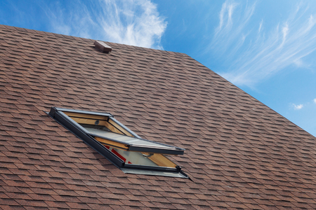 Roof with mansard windows and asphalt shingles.Open skylight on a roof shingles under constructionの写真素材