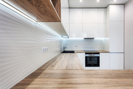 New bright modern kitchen with built in oven and chrome water tap and a wooden table topの写真素材