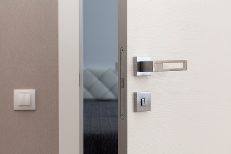 Open white door with metallic handle. The door to the bedroomの写真素材