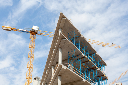 High-rise building under construction. The site with cranes against blue sky.の写真素材