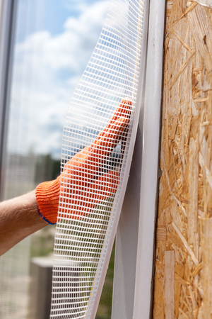 Construction worker wearing in gloves and install a special grid on the window.  Construction finishing works.の写真素材