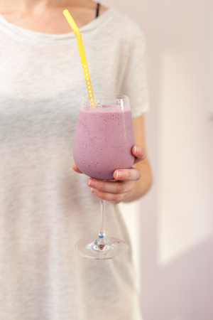 Woman holds a glass with pink cocktailの写真素材