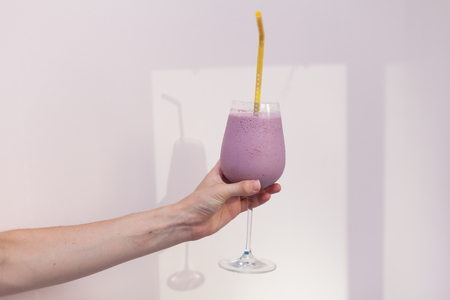 Girl holds a glass with pink cocktailの写真素材