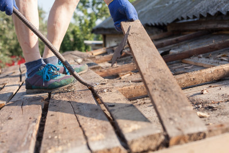 Worker demolishing old wooden boards from the roof  with crowbar toolの写真素材
