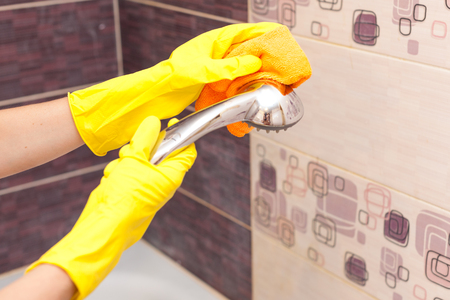 Hand in a yellow glove washes the shower.の写真素材