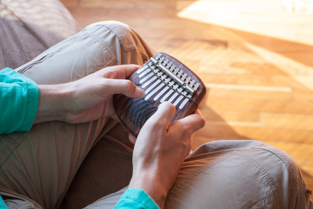 Man holding traditional African musical instrument kalimba in one's hands. Man playing on small kalimba. Clouseup musical instrumentの写真素材